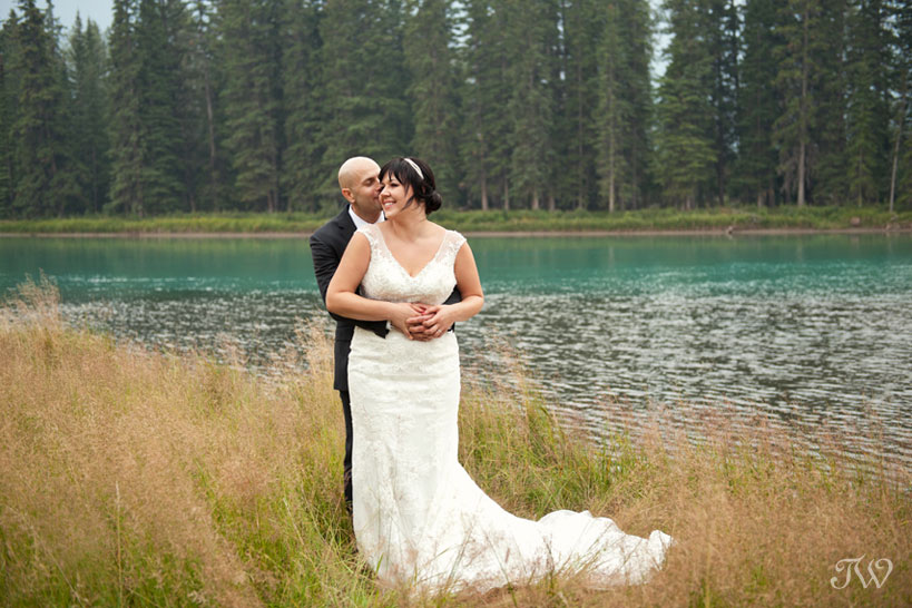 bride and groom pose by the Bow River in Banff captured by Tara Whittaker Photography