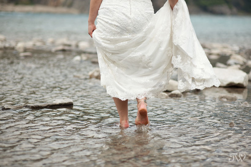 bride wades in the Bow River in the Town of Banff captured by Tara Whittaker Photography