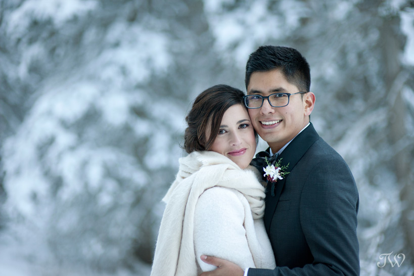 bride and groom pose near snow covered trees captured by Tara Whittaker Photography