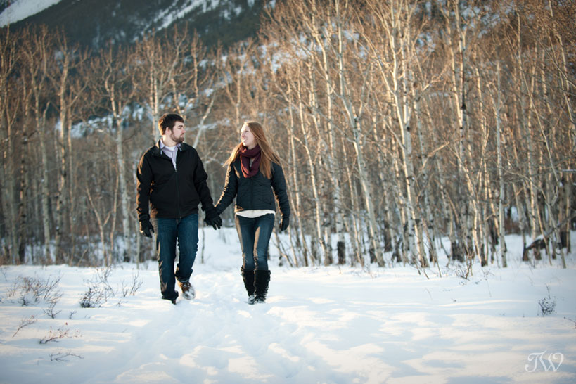 couple stroll in the woods during their winter engagement session