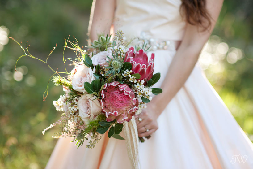 Rocky Mountain bride carries a bouquet of pink protea captured by Calgary wedding photographer Tara Whittaker
