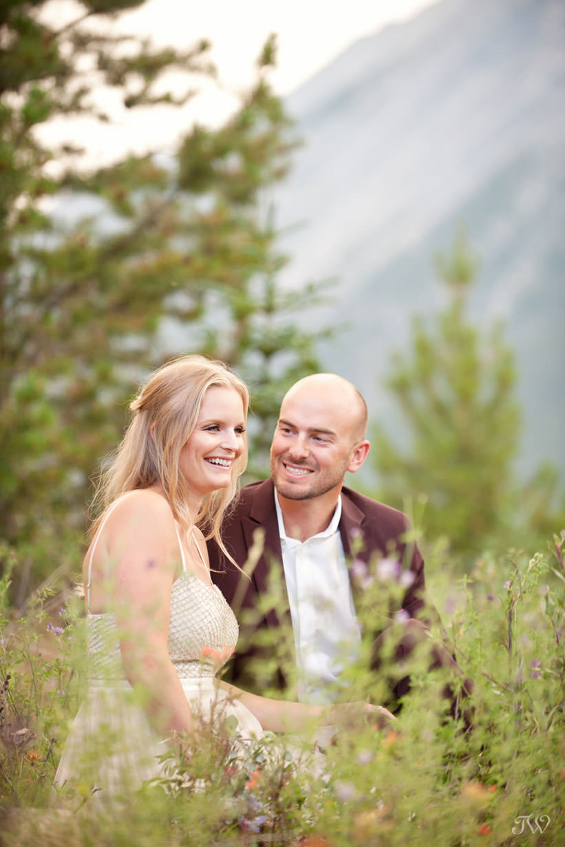 Couple sit in the wildflowers at their Spray Lakes engagement session captured by Tara Whittaker Photography