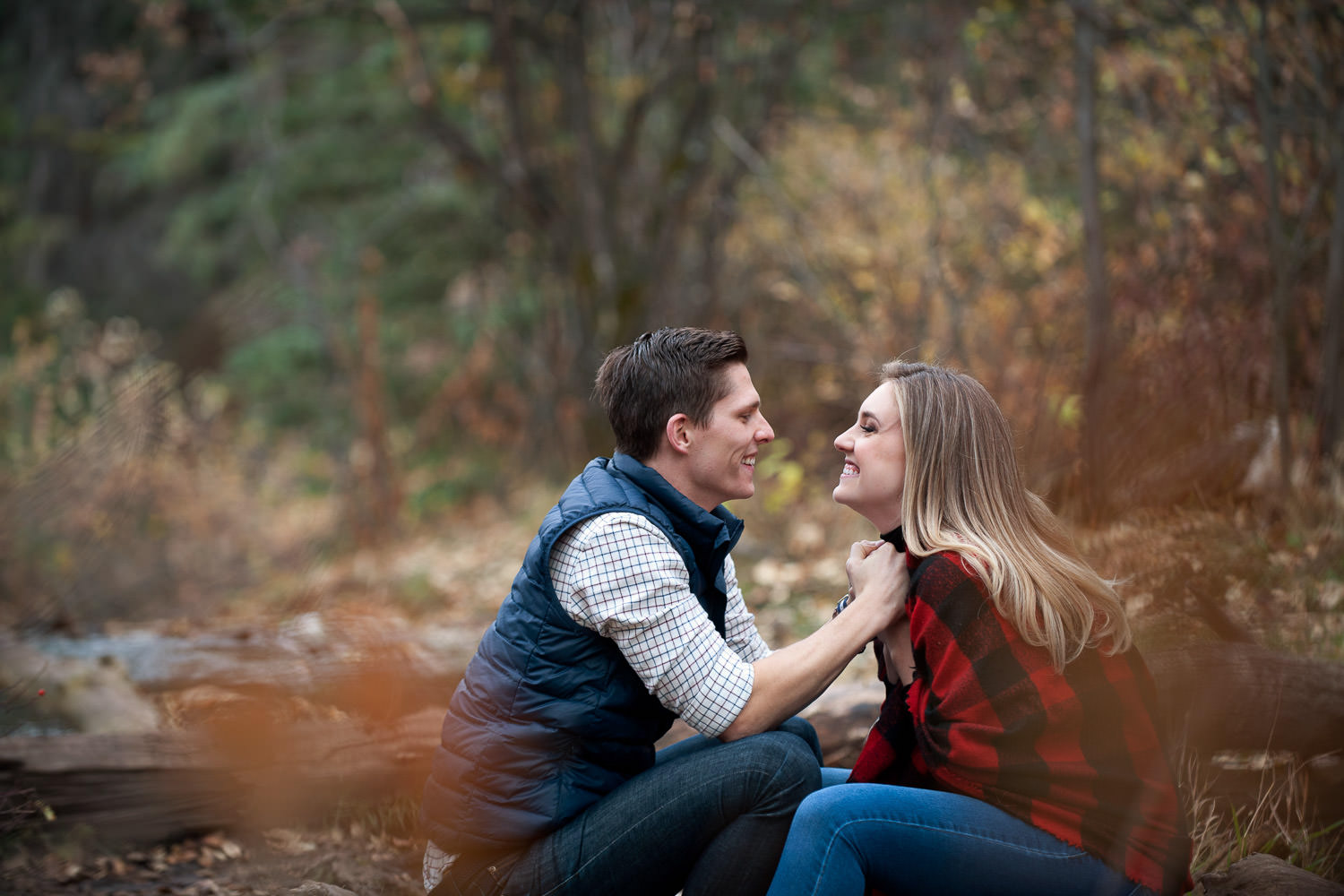 couple sit on a log during their engagement session captured by Tara Whittaker Photography