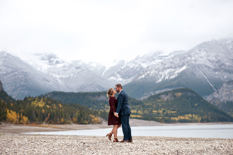 bride and groom share a kiss on the shore of Barrier Lake in Kananaskis captured by Tara Whittaker Photography