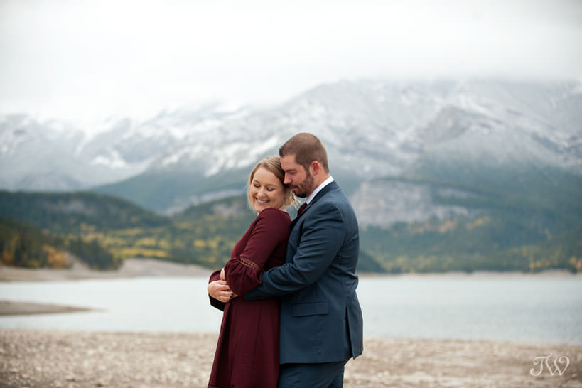 bride and groom embrace on the shore of Barrier Lake in Kananaskis captured by Tara Whittaker Photography