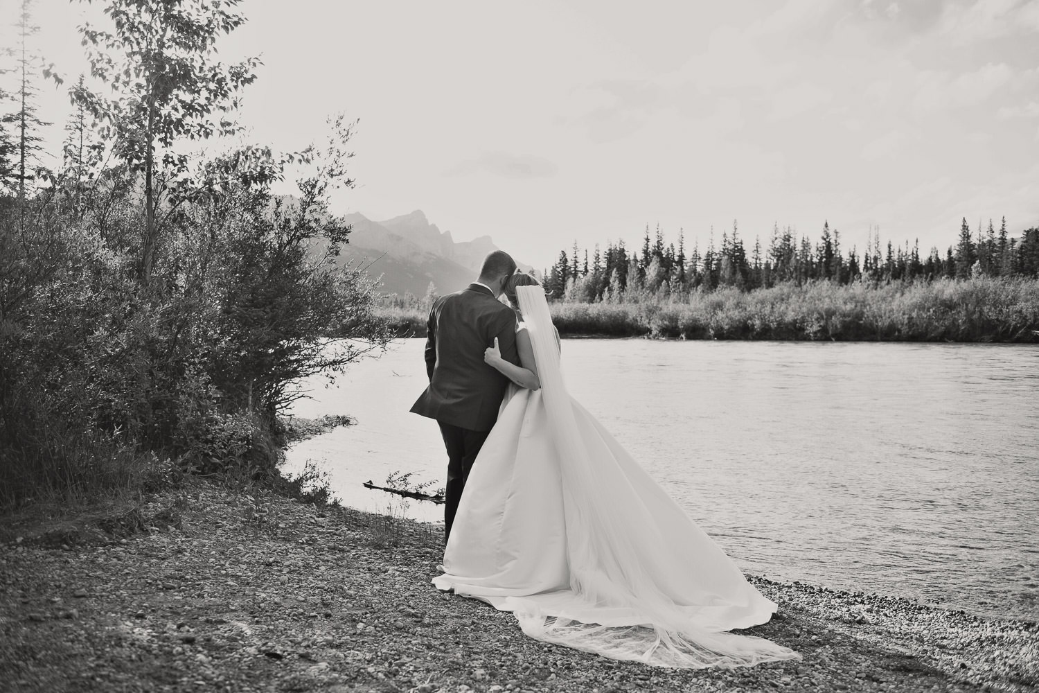 Bride and groom pose on the Bow River in Canmore captured by Tara Whittaker Photography