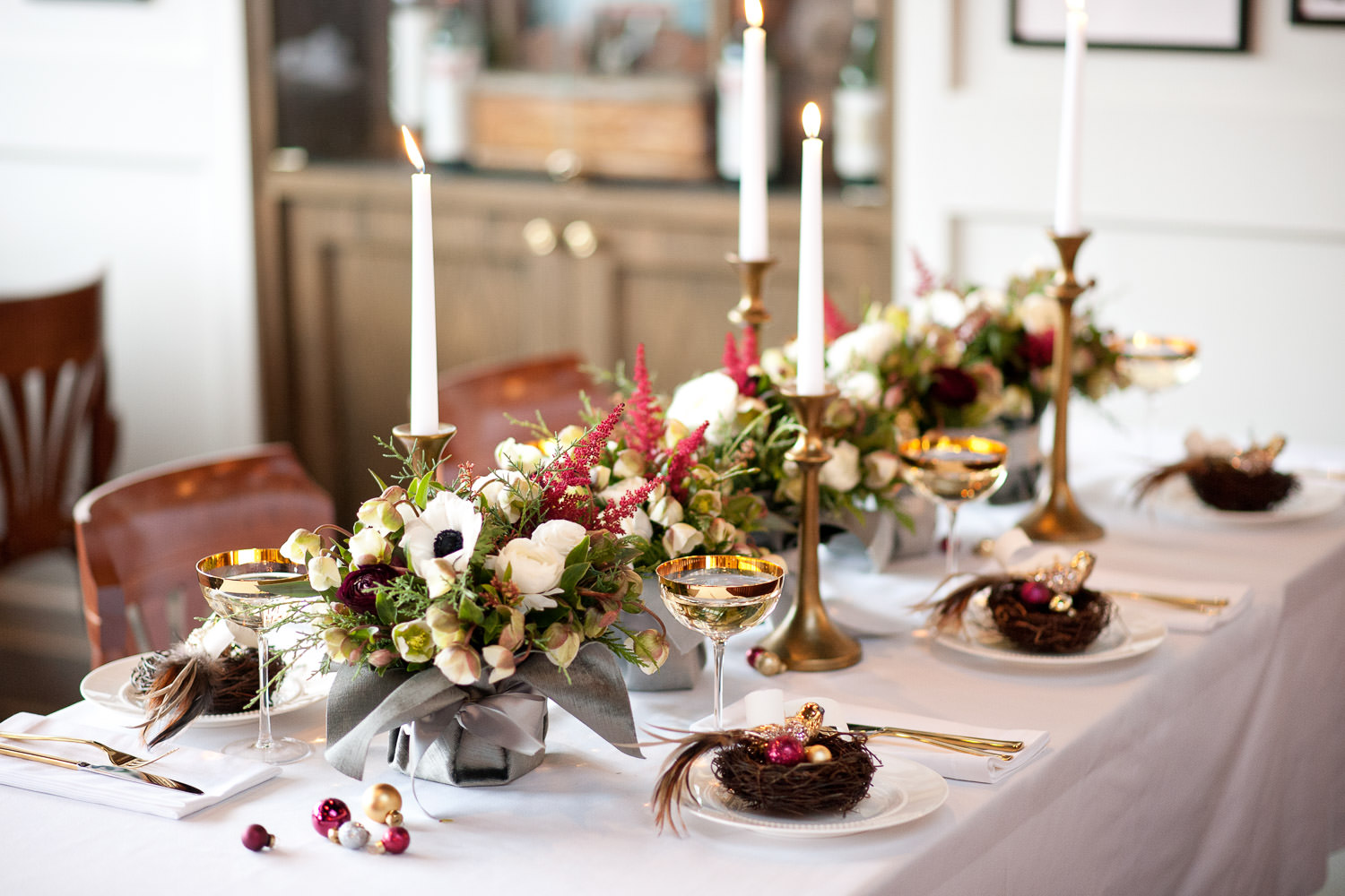 Holiday table with flowers, candles and gold champagne coupes captured by Tara Whittaker Photography